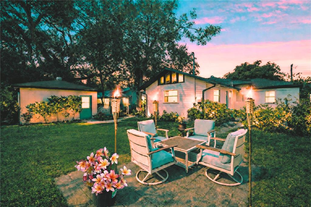 A backyard patio with a dining set, tiki torches, and a house in the background — 3704 W PLATT STREET, TAMPA, FL