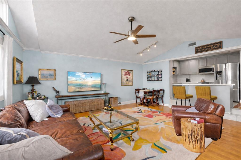 A living room with a leather sofa, glass coffee table, and an open kitchen area — 3704 W PLATT STREET, TAMPA, FL
