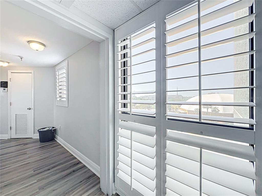A room with gray wood-look flooring, white walls, plantation shutters, and a view of a dome — 6165 CARRIER DRIVE UNIT 2602, ORLANDO, FL