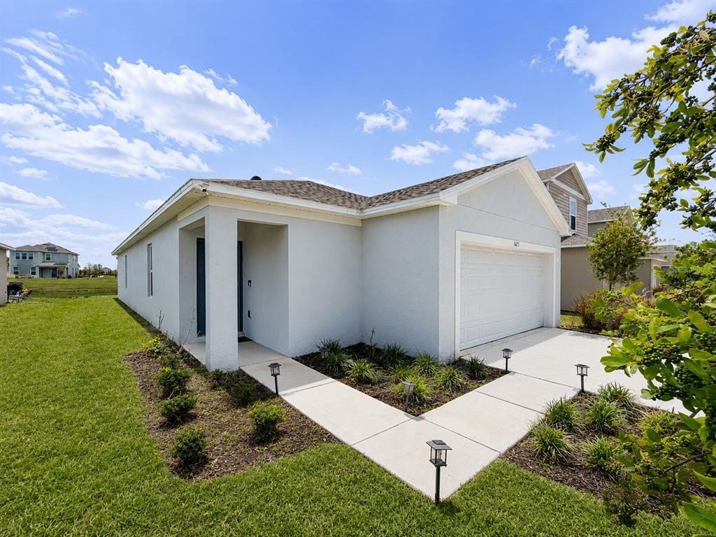 A light-colored, single-story house with a two-car garage and a concrete walkway — 5671 NISPERO WAY, KISSIMMEE, FL