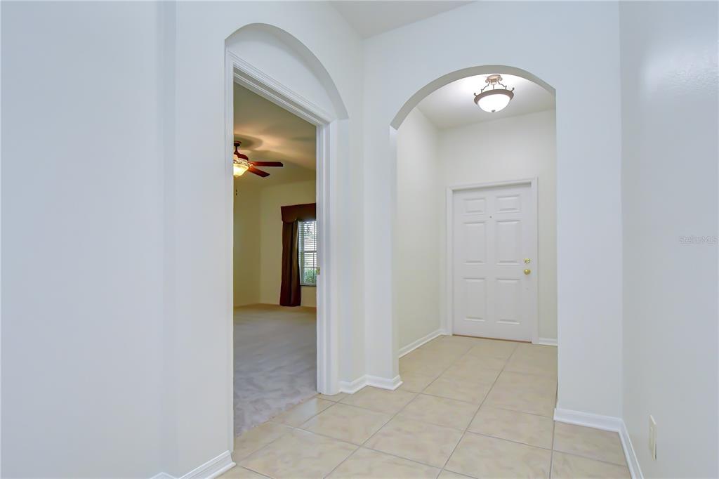 An entryway with tiled flooring leads to a white door and an arched doorway — 426 SUMMERLYN DRIVE, VALRICO, FL
