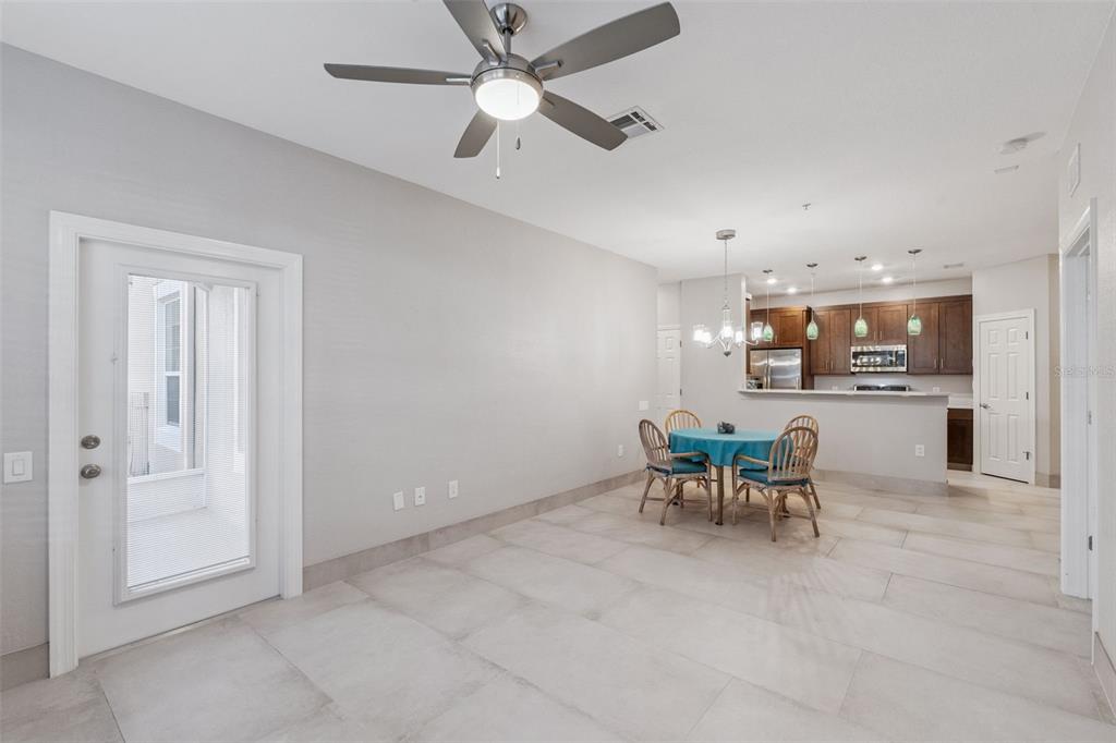 A dining area with tile floors, a ceiling fan, and an open kitchen in the background — 2484 SAN TECLA STREET UNIT 105, ORLANDO, FL