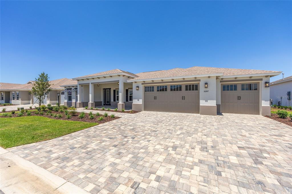 A single-story house with a paved driveway, three-car garage, and a covered front entryway — 10247 SW 82ND PLACE ROAD, OCALA, FL
