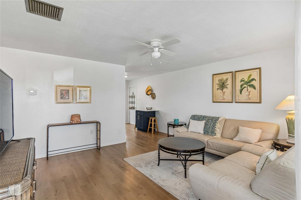 A living room features a beige sectional sofa, a round coffee table, and wood flooring — 3506 MURROW STREET, NEW PORT RICHEY, FL