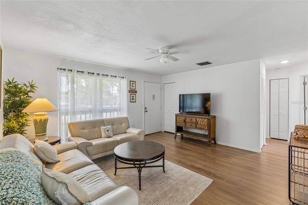 A living room features light wood-look flooring, a beige sofa, and a television on a console — 3506 MURROW STREET, NEW PORT RICHEY, FL