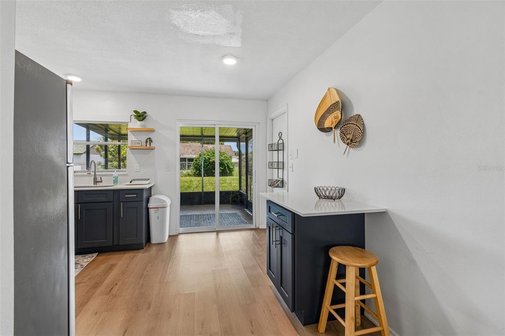A kitchen with dark blue cabinets, light wood flooring, and a sliding glass door — 3506 MURROW STREET, NEW PORT RICHEY, FL
