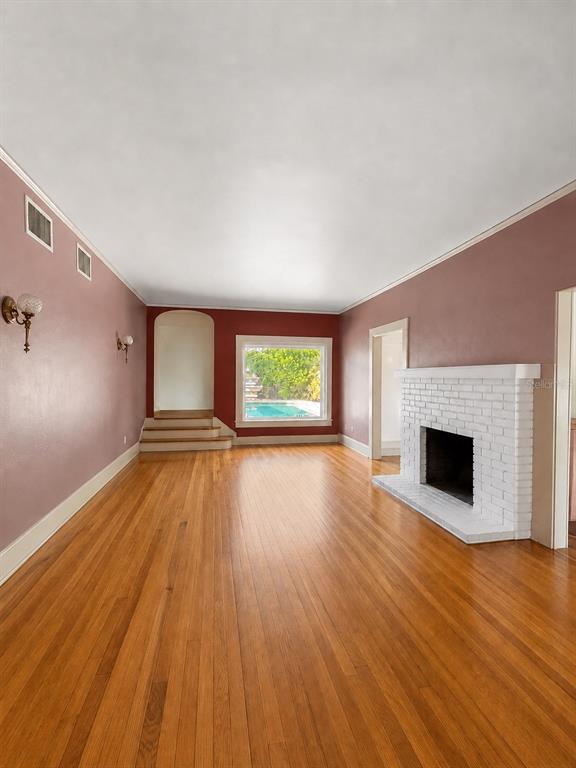 A living room features hardwood floors, a white brick fireplace, and steps leading to an archway — 4535 9TH AVENUE N, ST PETERSBURG, FL