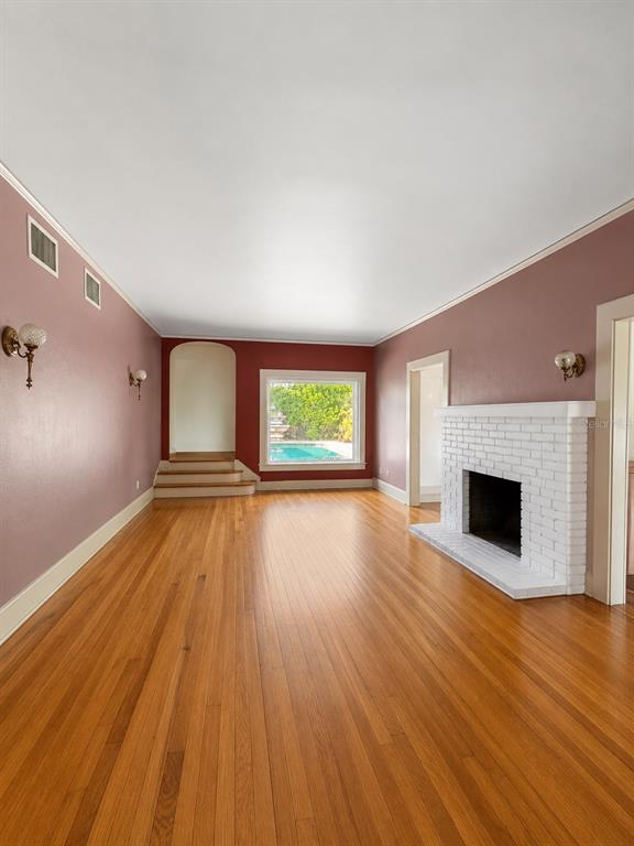 A living room with hardwood floors, a white brick fireplace, and a view of a pool — 4535 9TH AVENUE N, ST PETERSBURG, FL
