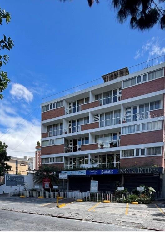 A multi-story brick and concrete apartment building features ground-floor retail storefronts and a parking lot — 15-25 AVE REFORMA, GUATEMALA CITY, OC