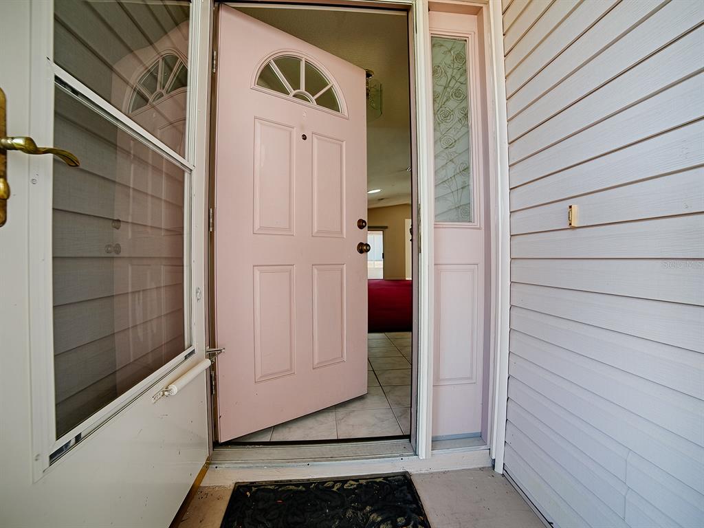 An open pink front door leads into a tiled entryway with a view of interior rooms — 752 OLD OAKS LANE, LEESBURG, FL