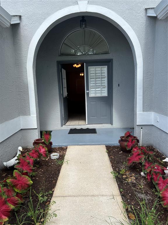 A concrete walkway leads to an arched entryway with a gray double door — 6381 EGRET DRIVE UNIT 14, LAKELAND, FL