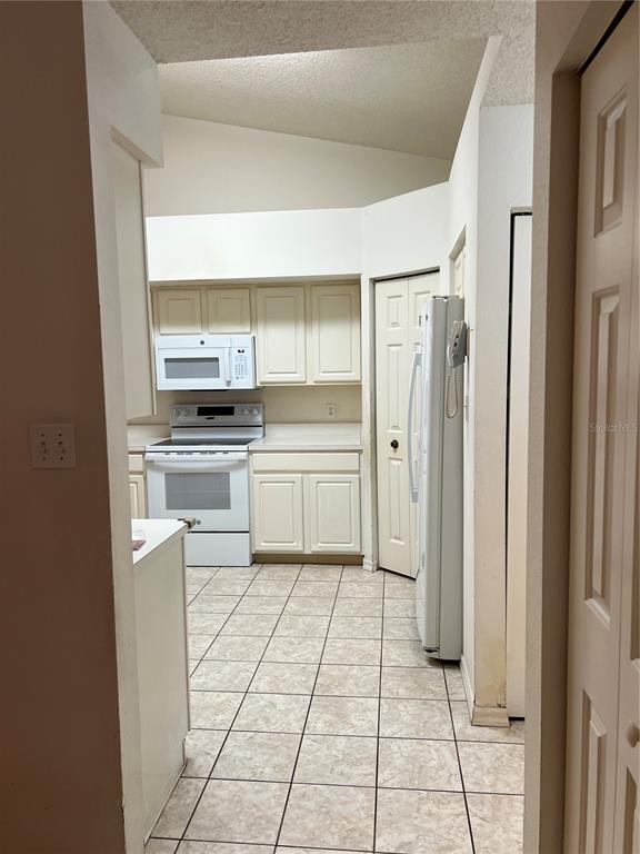 A kitchen with white cabinets, white appliances, and light-colored tile flooring — 6381 EGRET DRIVE UNIT 14, LAKELAND, FL