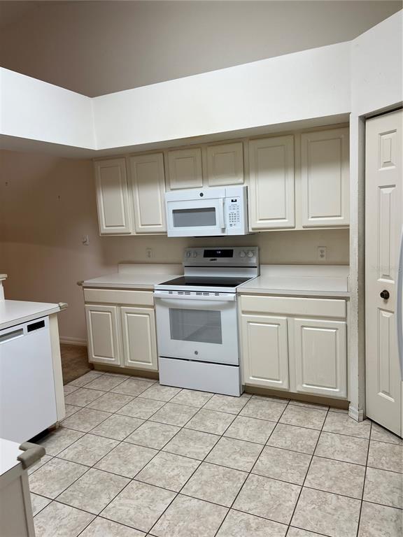 A kitchen features white cabinets, white appliances, and light-colored tile flooring — 6381 EGRET DRIVE UNIT 14, LAKELAND, FL