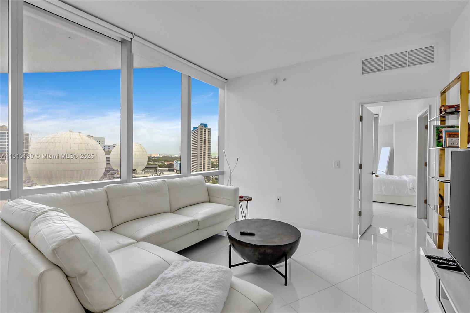 A modern living room features a white sectional sofa, a dark coffee table, and floor-to-ceiling windows — 851 NE 1st Ave # 1202, Miami FL 33132, MIAMI, FL