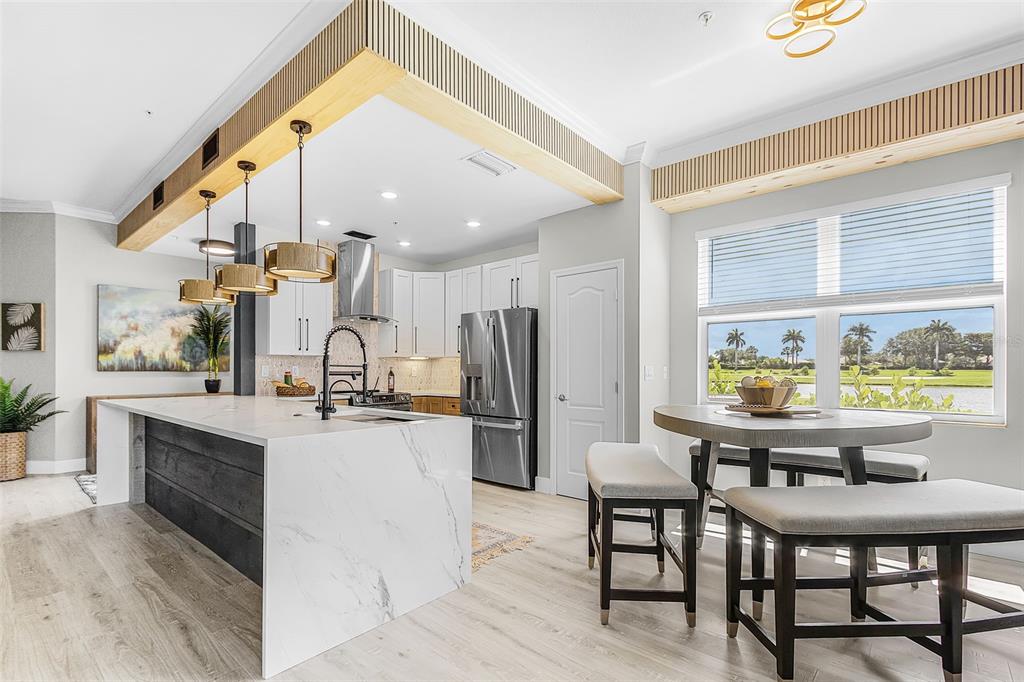 A modern kitchen features a marble-topped island, wood-slat ceiling accents, and a dining area — 14081 BLACK BEAUTY DRIVE UNIT 1111, PUNTA GORDA, FL