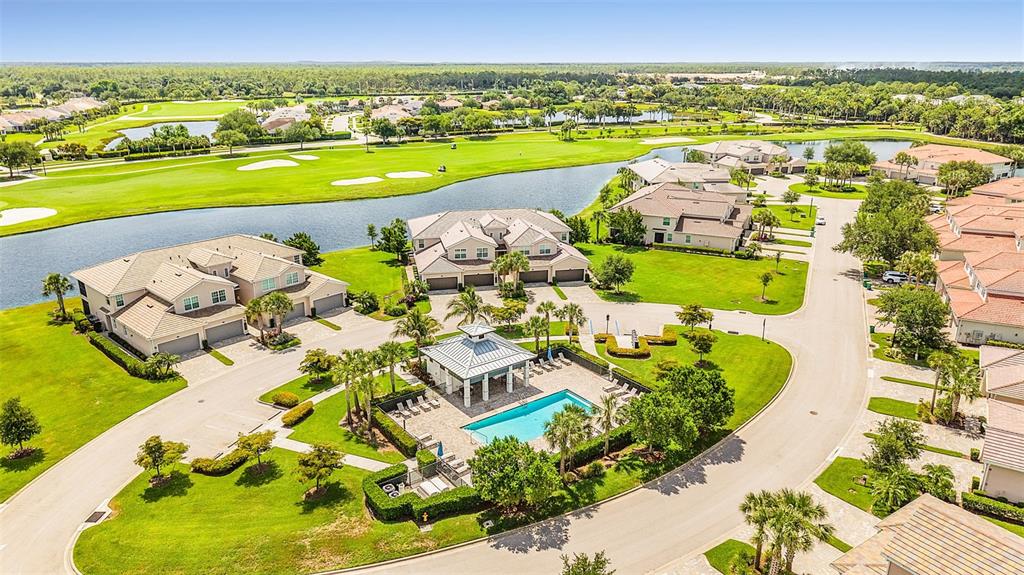 An aerial view shows a residential community with a swimming pool, clubhouse, and golf course — 14081 BLACK BEAUTY DRIVE UNIT 1111, PUNTA GORDA, FL