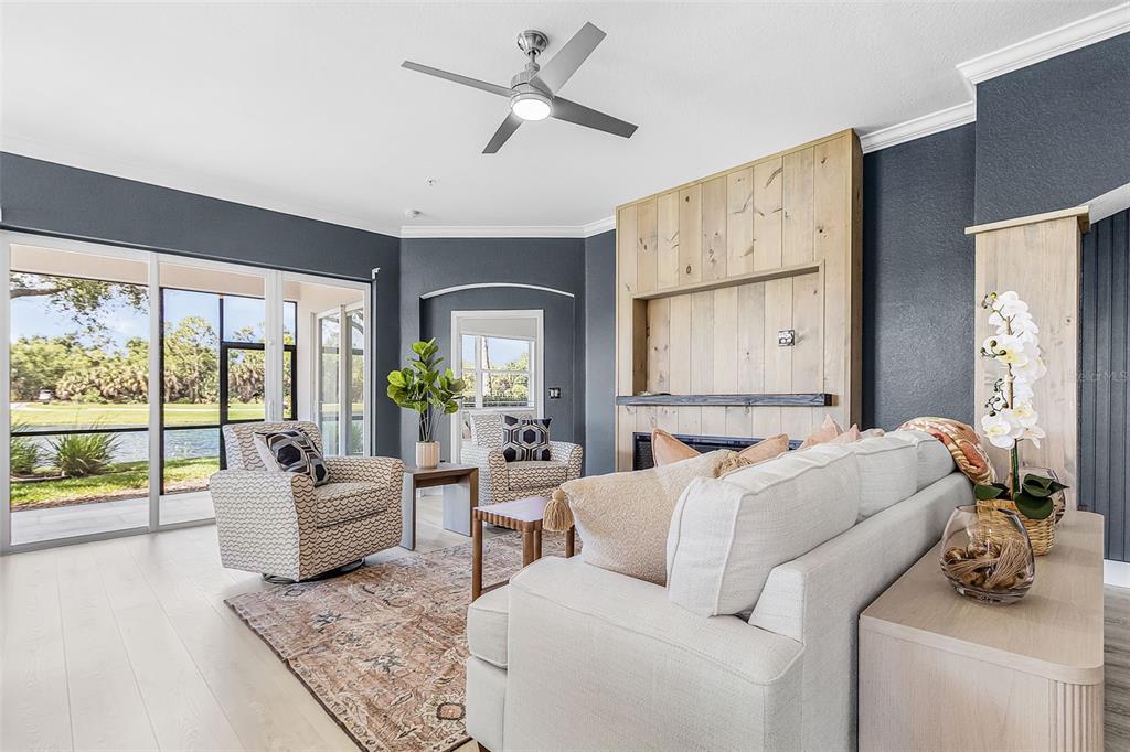 A living room features a fireplace with wood paneling, a sofa, armchairs, and sliding glass doors — 14081 BLACK BEAUTY DRIVE UNIT 1111, PUNTA GORDA, FL