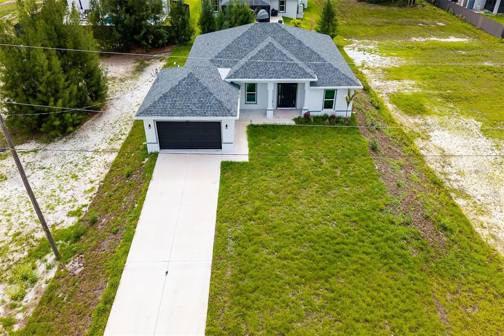 An aerial view shows a single-story house with a gray roof and a concrete driveway — 2221 NW 43RD AVENUE, CAPE CORAL, FL