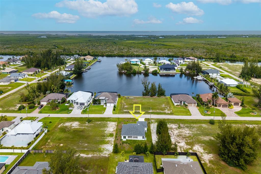An aerial view shows a single-story house with a gray roof near a canal — 2221 NW 43RD AVENUE, CAPE CORAL, FL