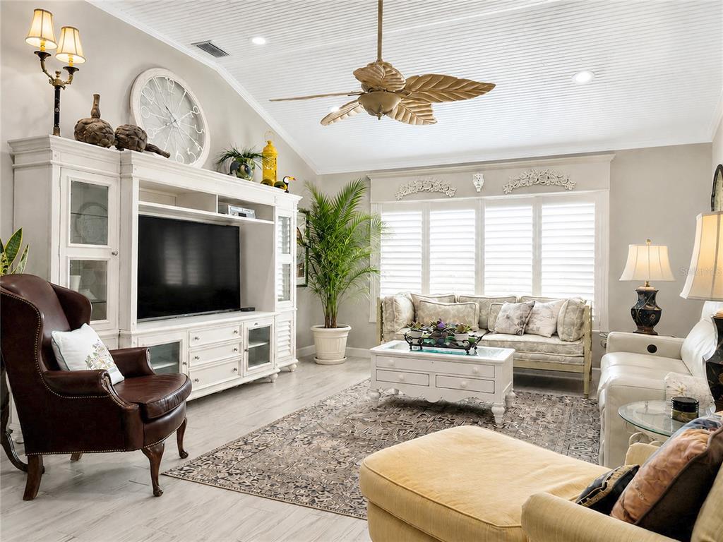 A living room features a white entertainment center, a brown leather chair, and a ceiling fan — 853 WINCHESTER COURT, THE VILLAGES, FL