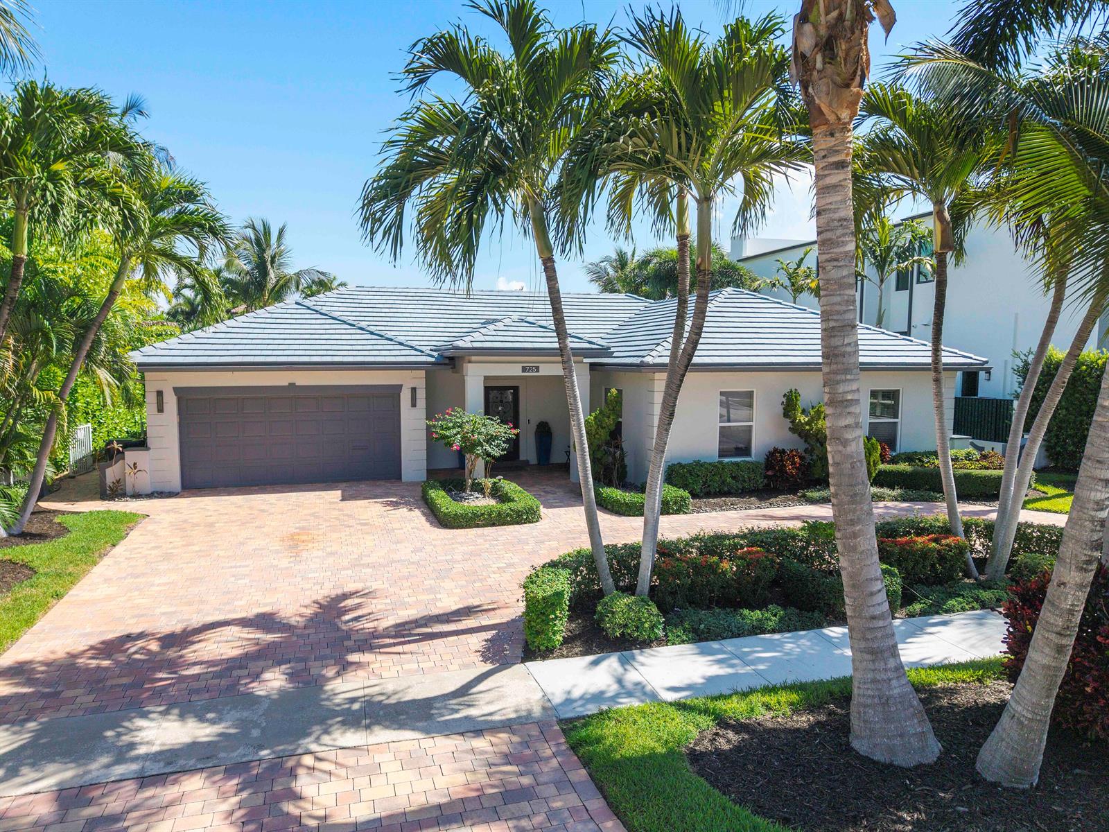 A single-story house with a gray tile roof, paver driveway, and palm trees in front — 725 NE 36th Street, Boca Raton FL 33431, BOCA RATON, FL