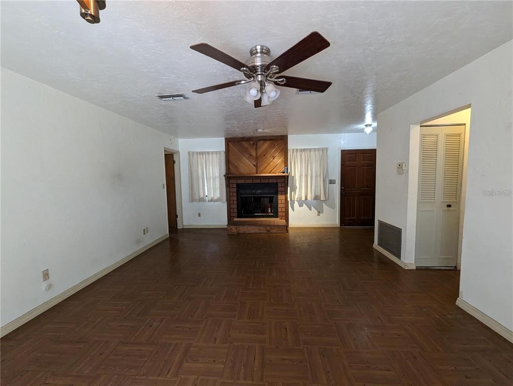 A living room features a wood-paneled fireplace, parquet flooring, and a ceiling fan — 721 SW 127TH STREET, NEWBERRY, FL