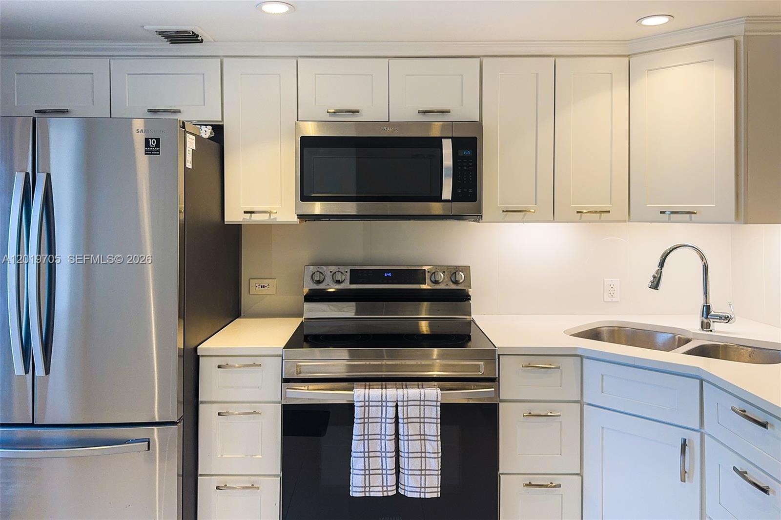 A kitchen features white cabinets, stainless steel appliances, and white countertops — 3200 N Palm Aire Dr # 207, Pompano Beach FL 33069, POMPANO BEACH, FL