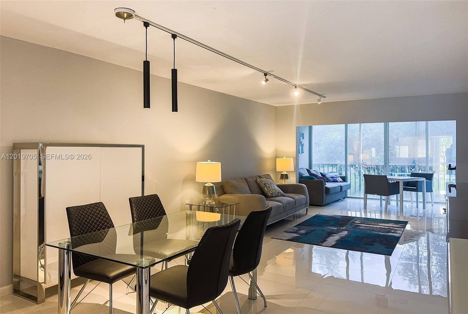 A dining and living area features a glass table, track lighting, and tiled floors — 3200 N Palm Aire Dr # 207, Pompano Beach FL 33069, POMPANO BEACH, FL