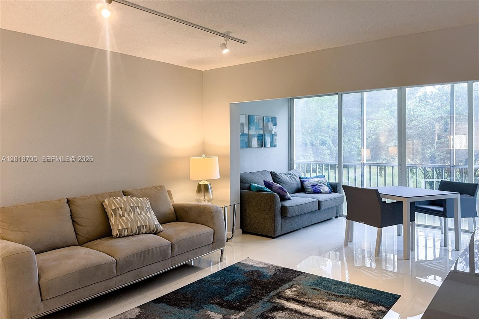 A living room features a beige sofa, a dark rug, and a dining area — 3200 N Palm Aire Dr # 207, Pompano Beach FL 33069, POMPANO BEACH, FL