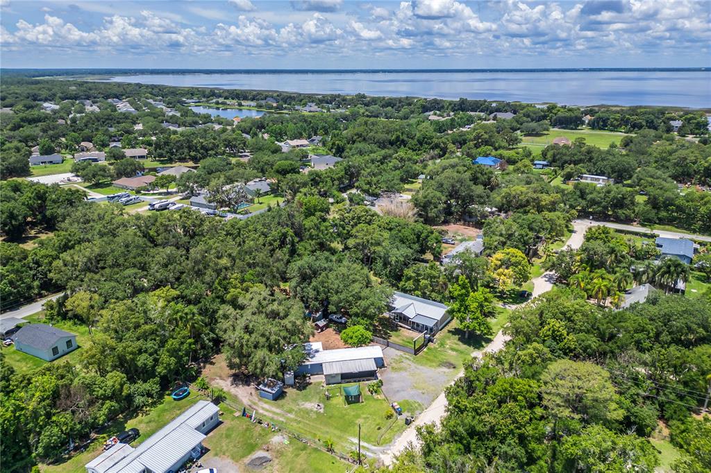 An aerial view shows several houses nestled among dense trees near a large lake — 4960 YUKON STREET, ST CLOUD, FL