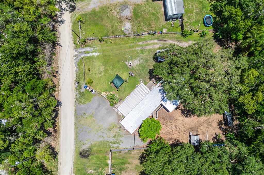 An aerial view shows a house with a metal roof, a gravel driveway, and trees — 4960 YUKON STREET, ST CLOUD, FL