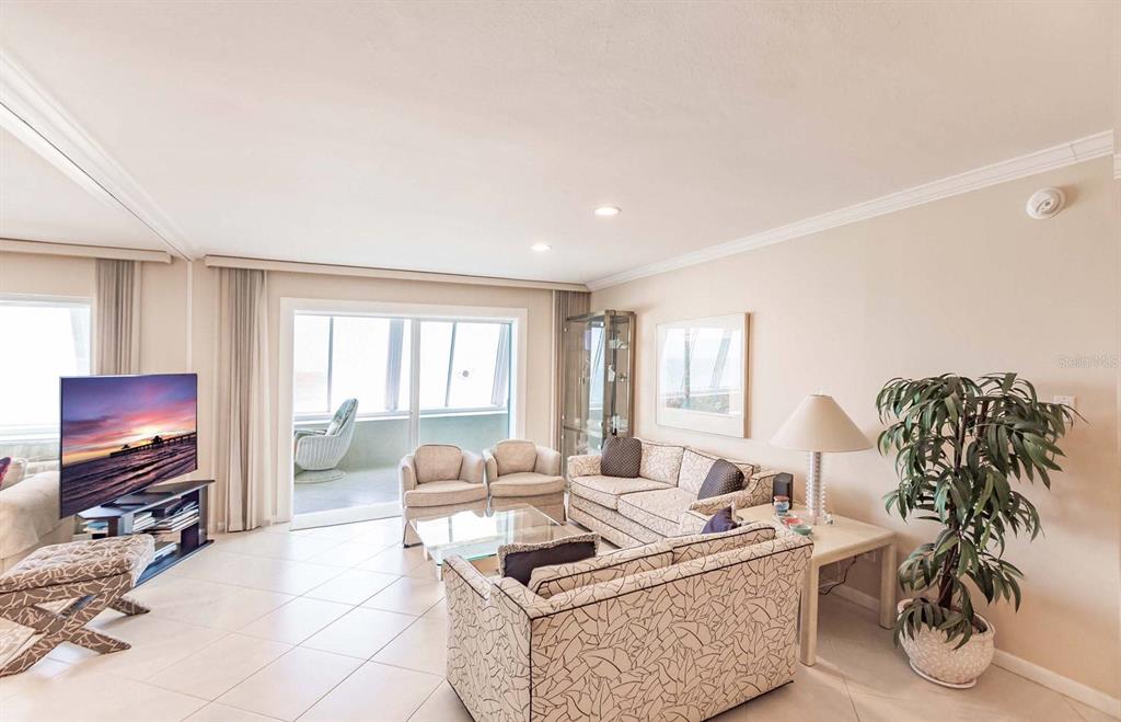 A living room features tile flooring, a television, a sofa, armchairs, and a balcony view — 1055 W PEPPERTREE DRIVE UNIT 802AA, SARASOTA, FL