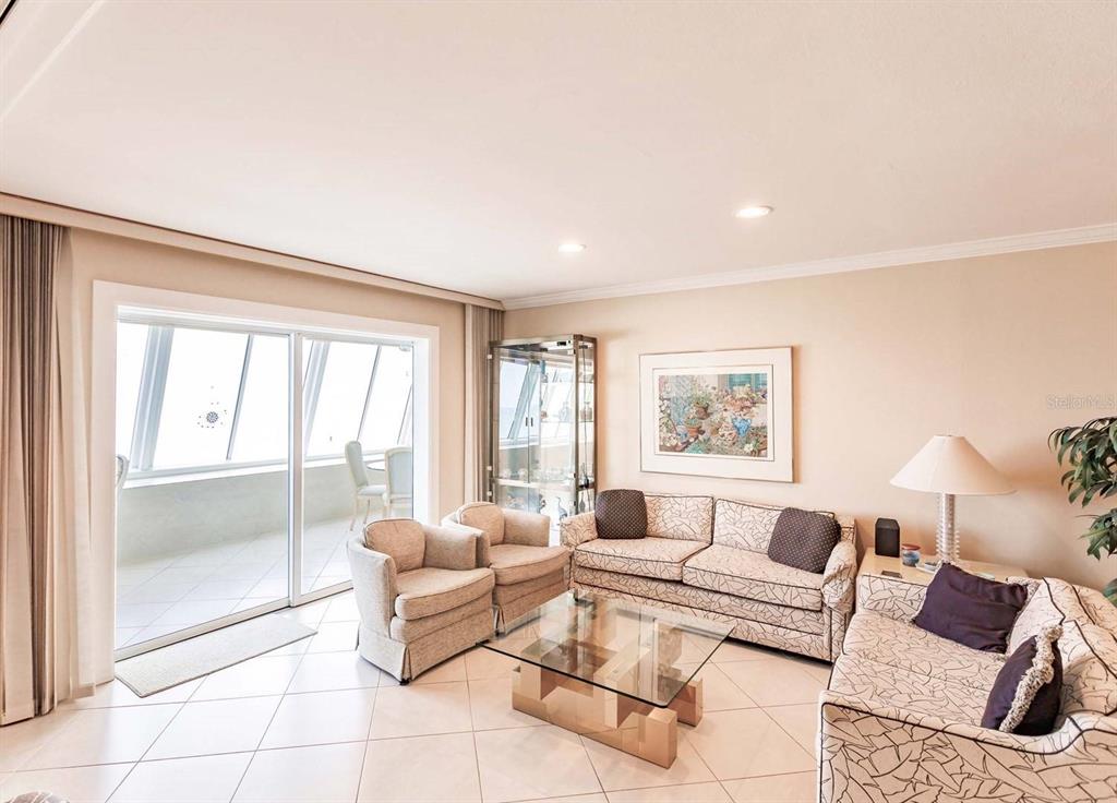 A living room features tile floors, a glass coffee table, and a sliding glass door — 1055 W PEPPERTREE DRIVE UNIT 802AA, SARASOTA, FL