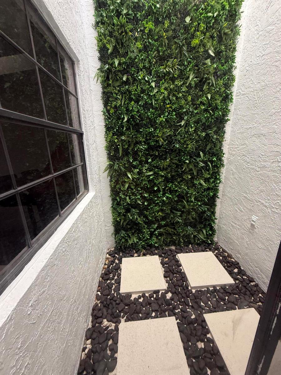 A small outdoor courtyard features a vertical garden wall, stone pavers, and black decorative rocks — 5161 NW 11th Lane, Deerfield Beach FL 33064, DEERFIELD BEACH, FL