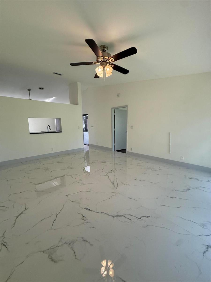 An empty room features white marble-look tile flooring, a ceiling fan, and a pass-through window — 5161 NW 11th Lane, Deerfield Beach FL 33064, DEERFIELD BEACH, FL