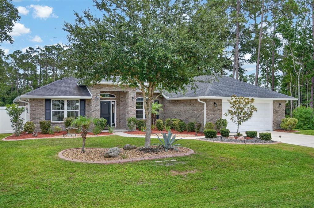 A single-story brick house with a dark roof, a front lawn, and a two-car garage — 24 LINCOLN LANE, PALM COAST, FL