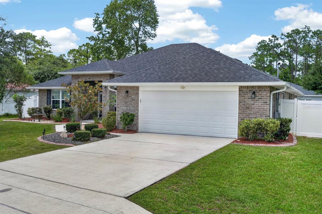 A single-story brick house with a two-car garage and a concrete driveway — 24 LINCOLN LANE, PALM COAST, FL