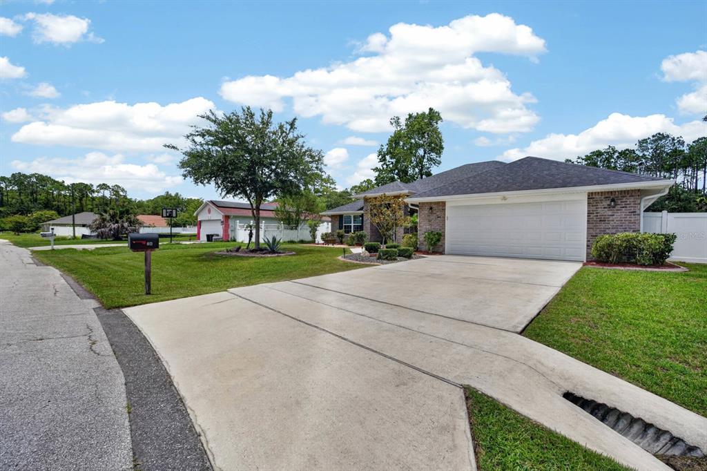 A single-story brick house with a two-car garage and a concrete driveway — 24 LINCOLN LANE, PALM COAST, FL