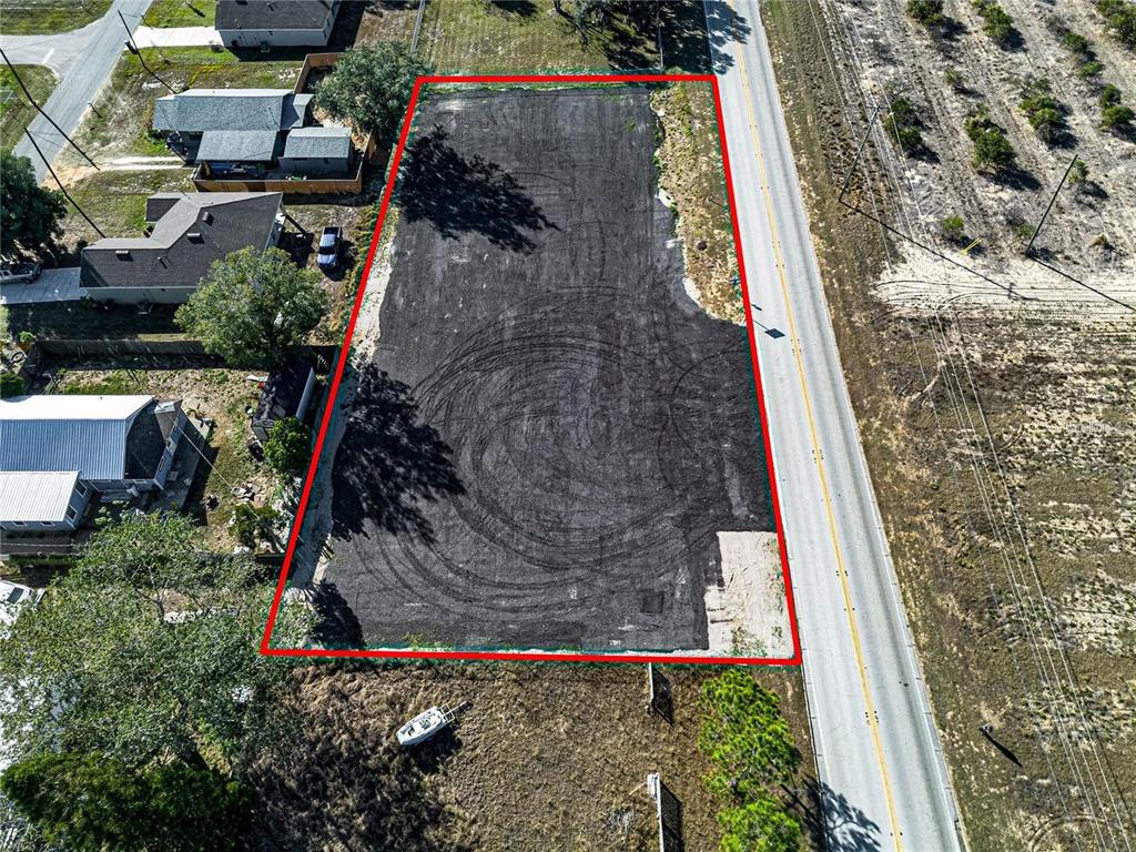 An aerial view shows a rectangular, cleared dirt lot outlined in red next to a road — S SCENIC HIGHWAY, FROSTPROOF, FL