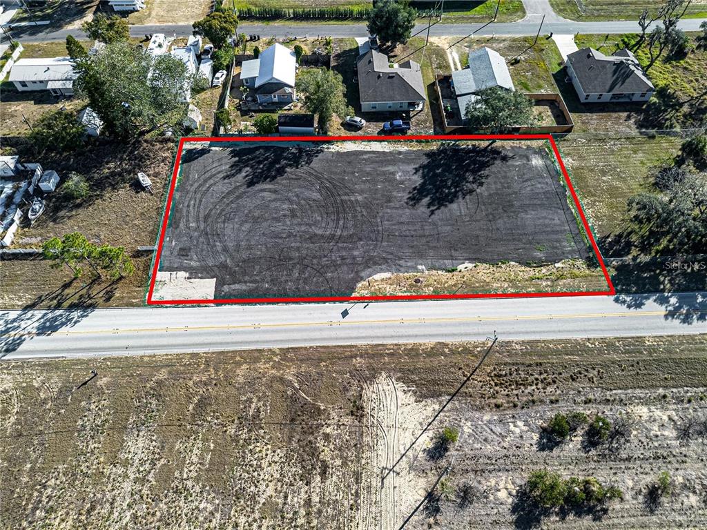 An aerial view shows a rectangular, cleared lot outlined in red next to a road — S SCENIC HIGHWAY, FROSTPROOF, FL
