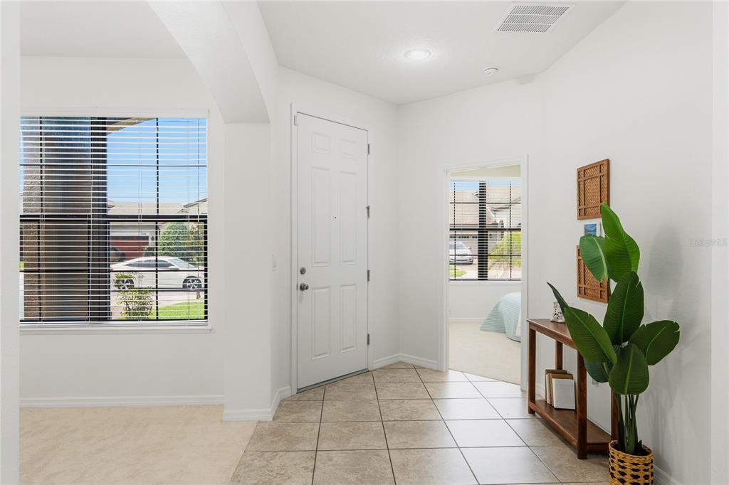 A tiled entryway features a white front door, a side window, and a potted plant — 5160 SASSARI AVENUE, ST CLOUD, FL