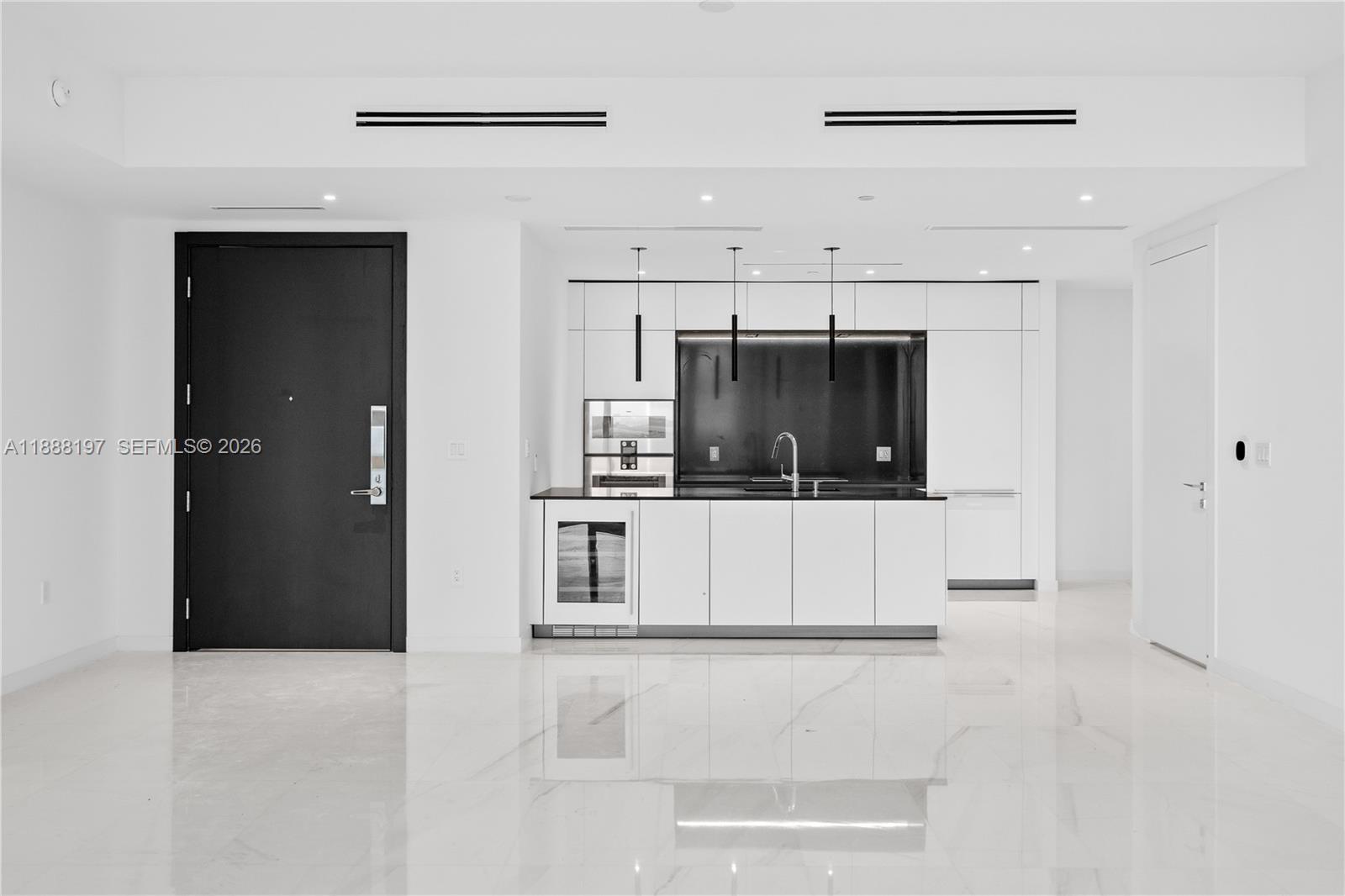 A modern kitchen features white cabinetry, a black backsplash, and a wine cooler — 300 Biscayne Blvd Way # 1103, Miami FL 33131, MIAMI, FL