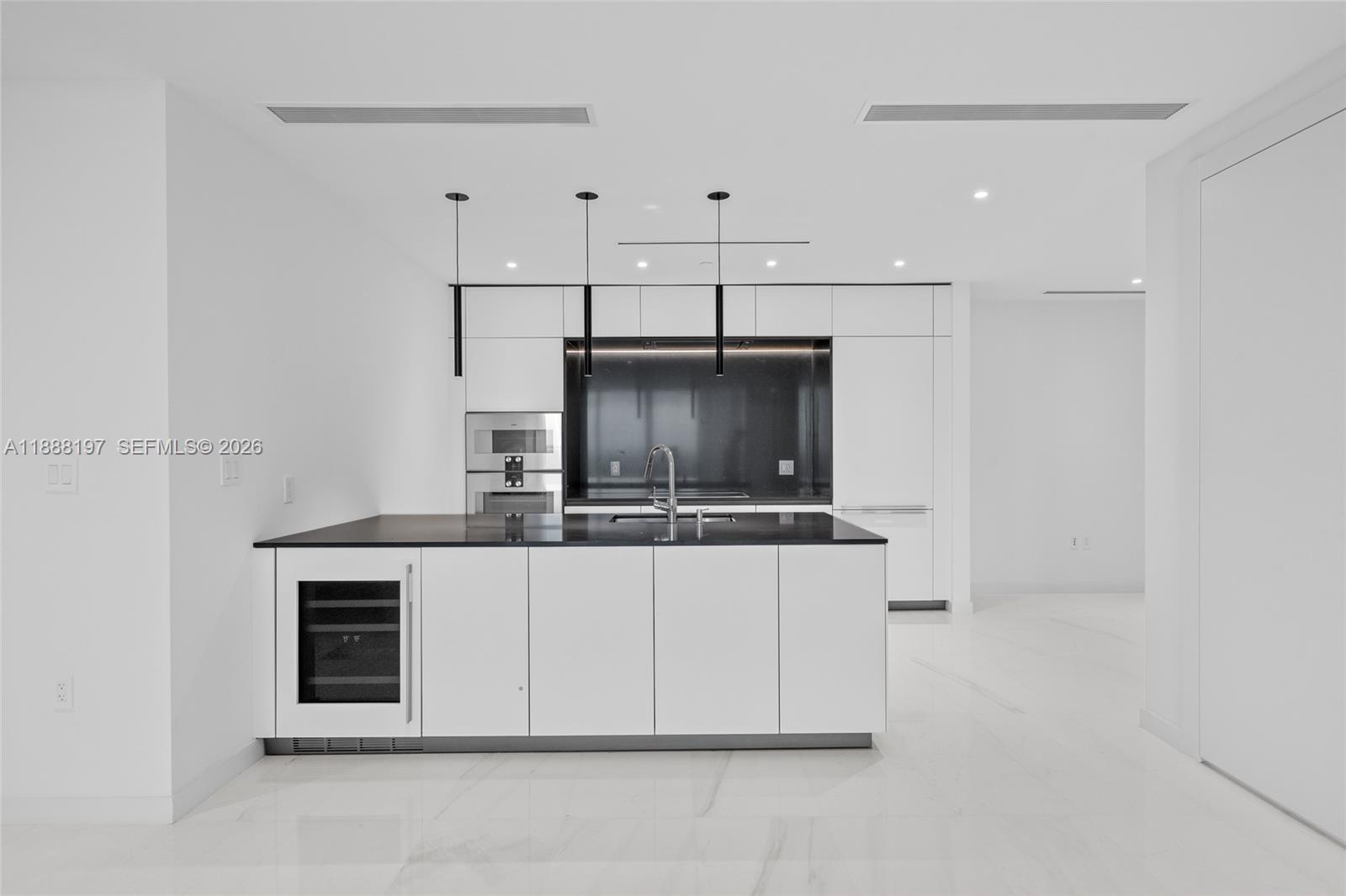 A modern kitchen features white cabinetry, a black countertop island, and a wine refrigerator — 300 Biscayne Blvd Way # 1103, Miami FL 33131, MIAMI, FL