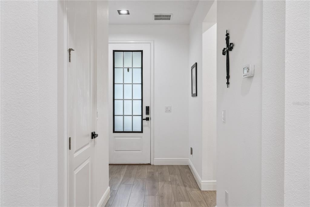A white front door with a glass pane stands at the end of a hallway — 15524 HONEYBELL DRIVE, WINTER GARDEN, FL