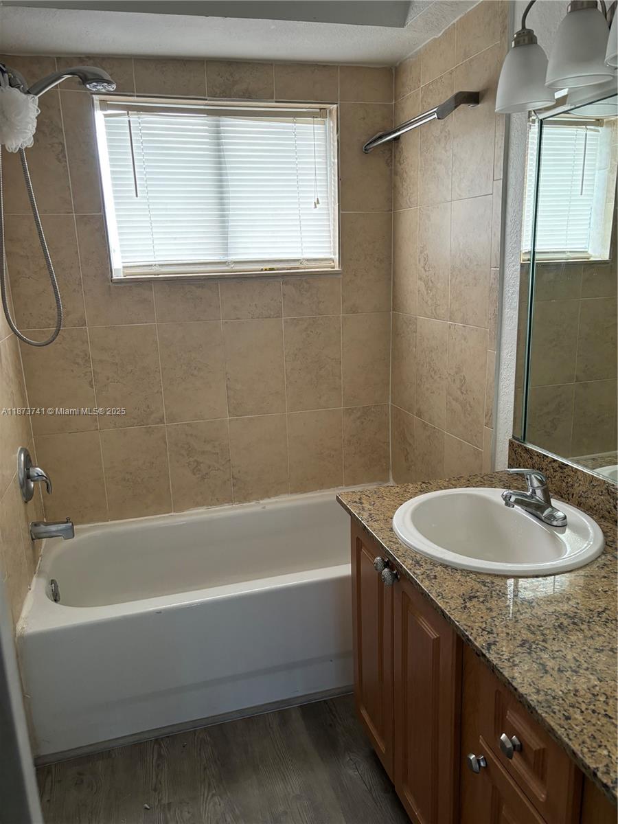 A bathroom features a tiled tub-shower combination, a granite vanity countertop, and a wooden cabinet — 7701 SW 88th St # B224, Miami FL 33156, MIAMI, FL