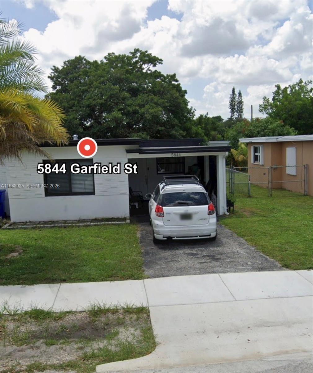 A white single-story house features a flat roof, a carport, and a paved driveway — 5844 Garfield St, Hollywood FL 33021, HOLLYWOOD, FL