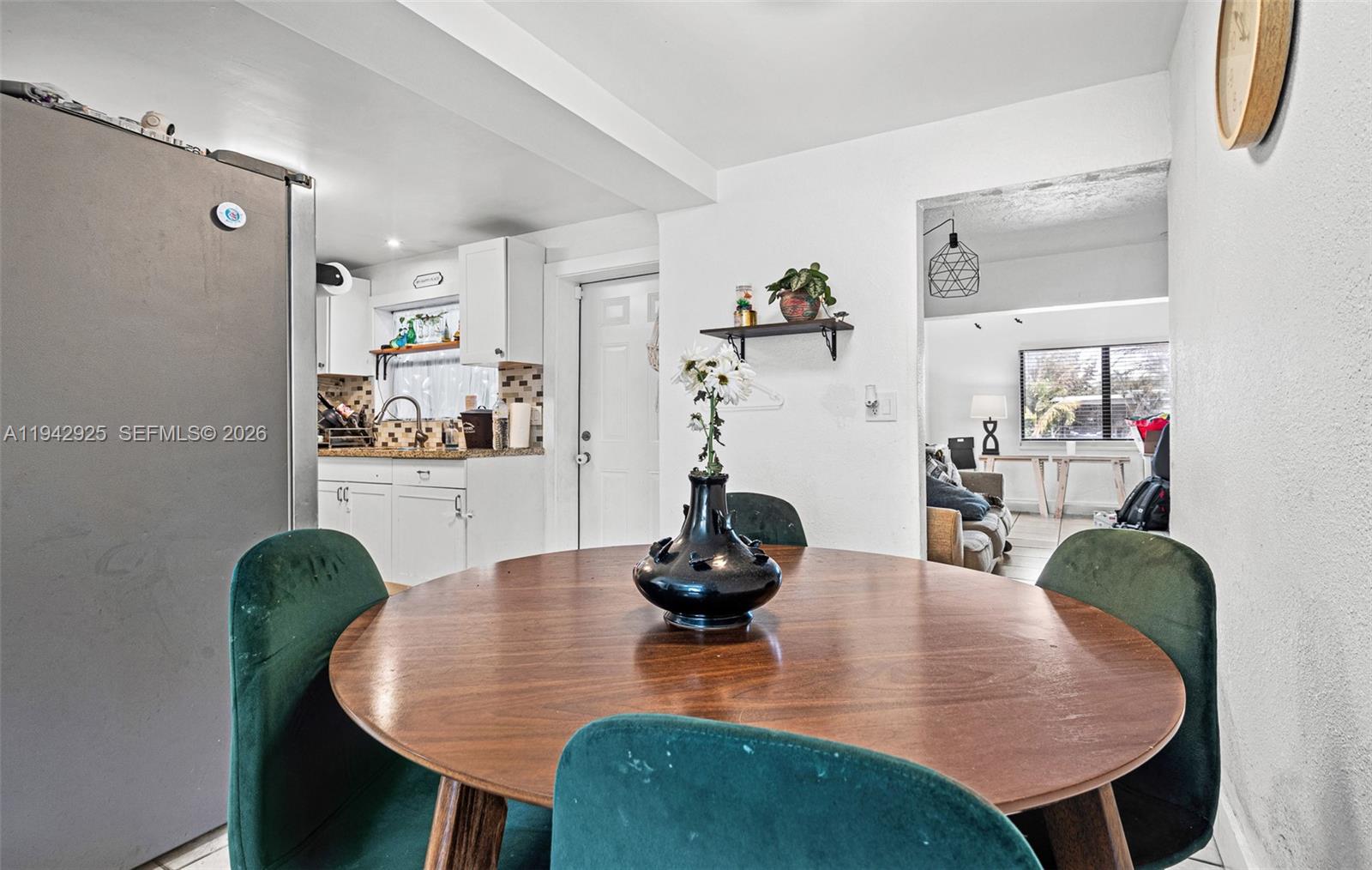A dining area with a round wooden table and green chairs opens into a kitchen — 5844 Garfield St, Hollywood FL 33021, HOLLYWOOD, FL