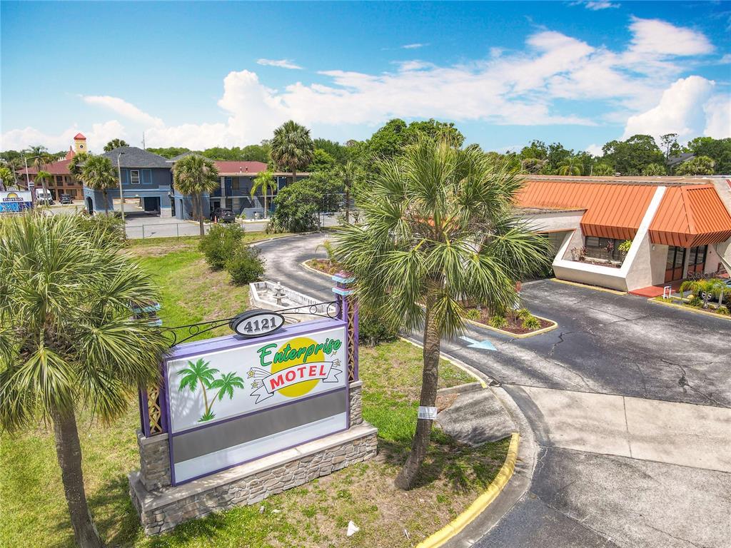 An exterior view of a motel with a prominent sign and a palm-lined driveway — 4121 W VINE STREET, KISSIMMEE, FL