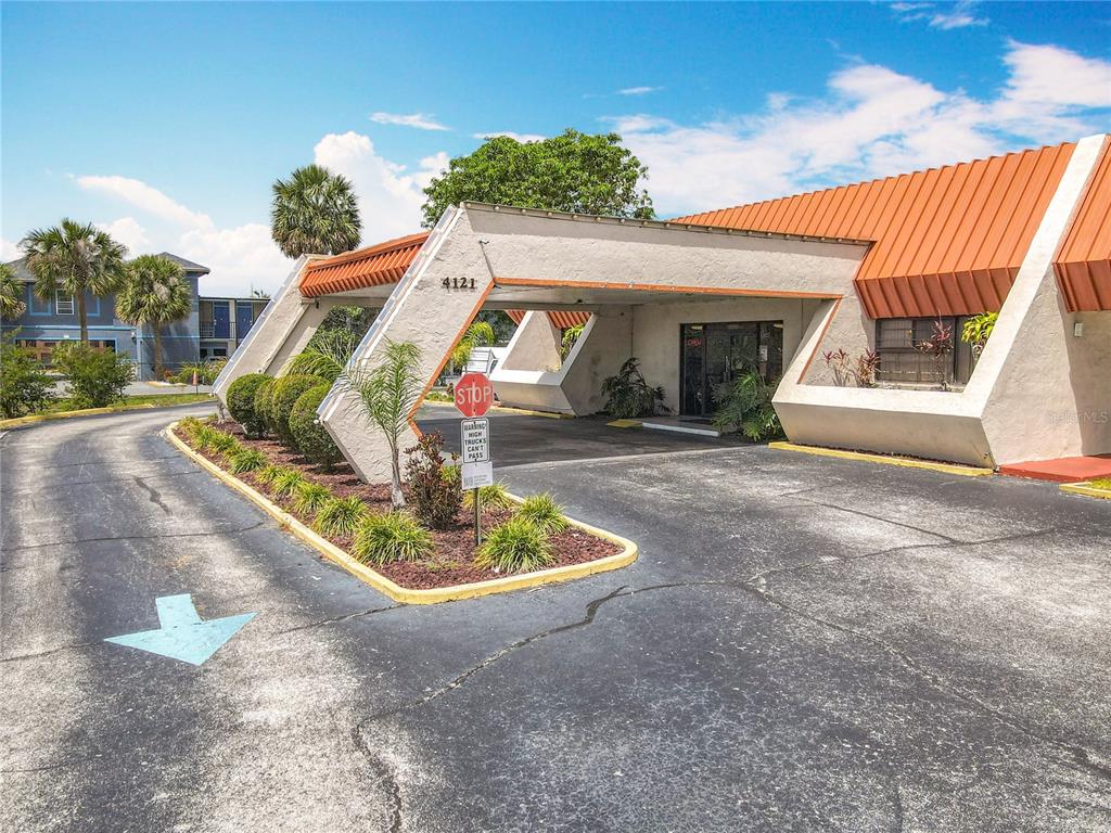 An exterior view of a commercial building with a large, angled, orange-roofed porte-cochere — 4121 W VINE STREET, KISSIMMEE, FL