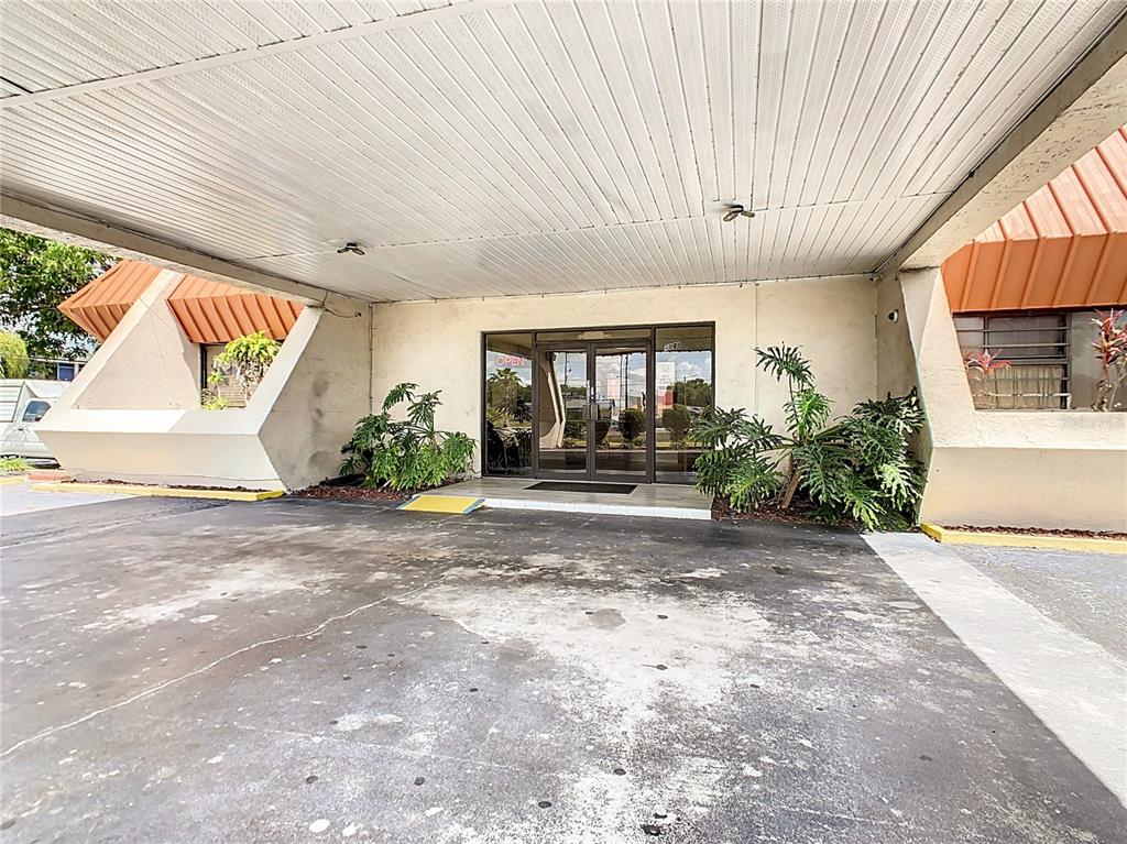 A covered entrance leads to a glass-paned doorway flanked by large green plants — 4121 W VINE STREET, KISSIMMEE, FL